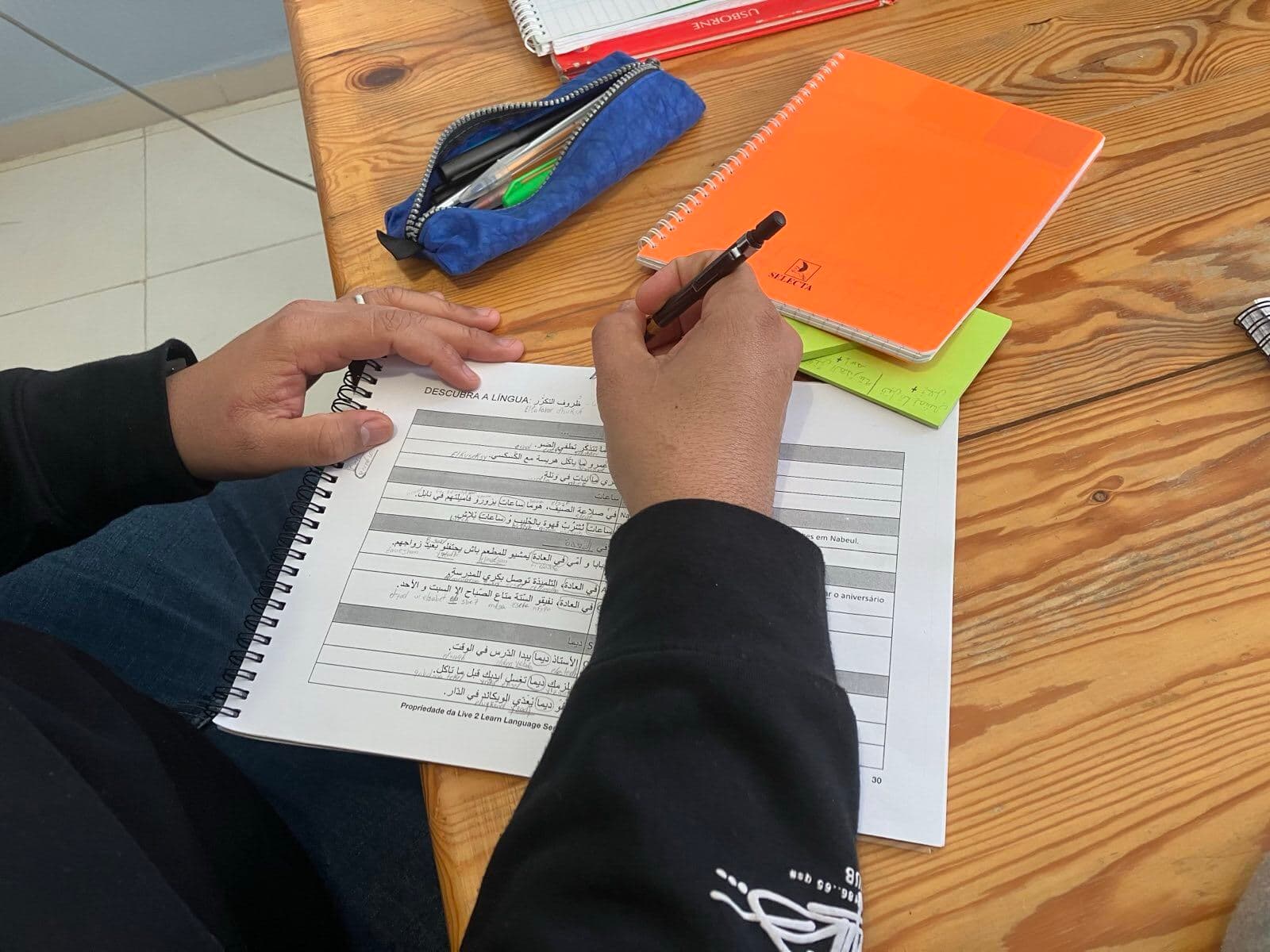 Hands arranging Arabic words during a reading lesson